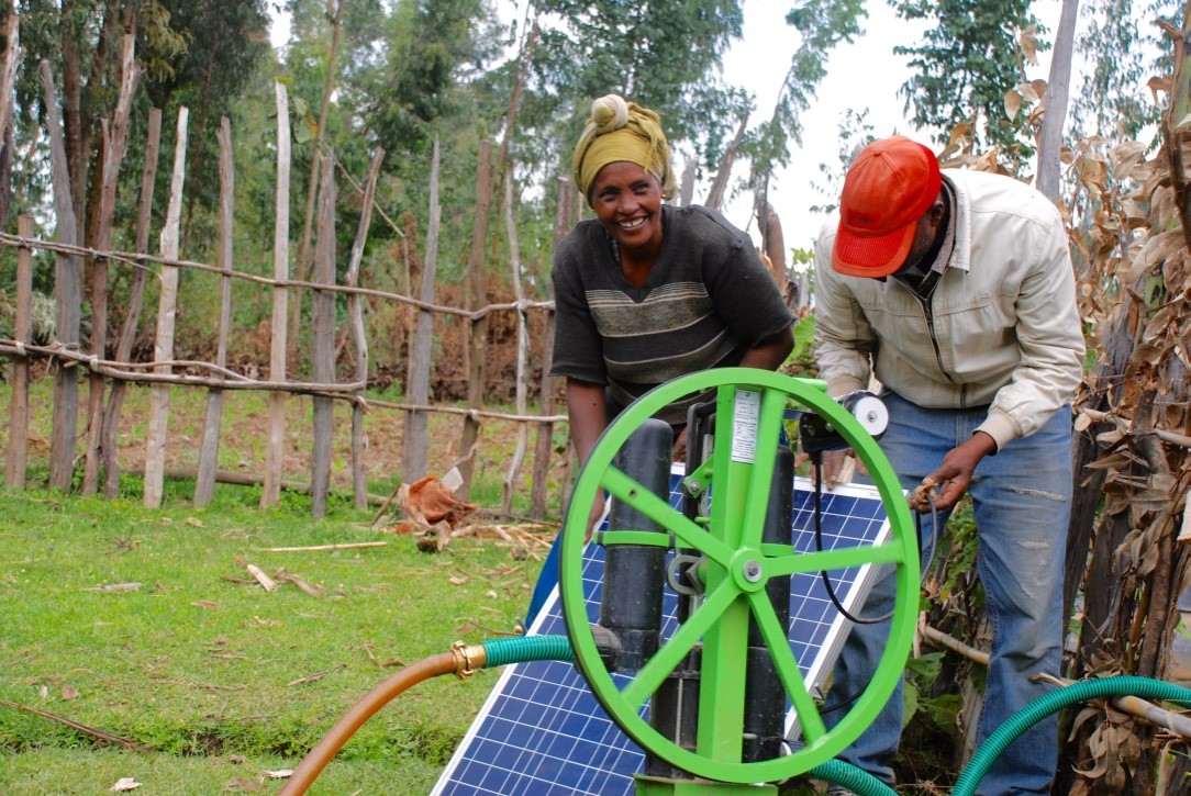 Two people working on a small solar powered irrigation pump