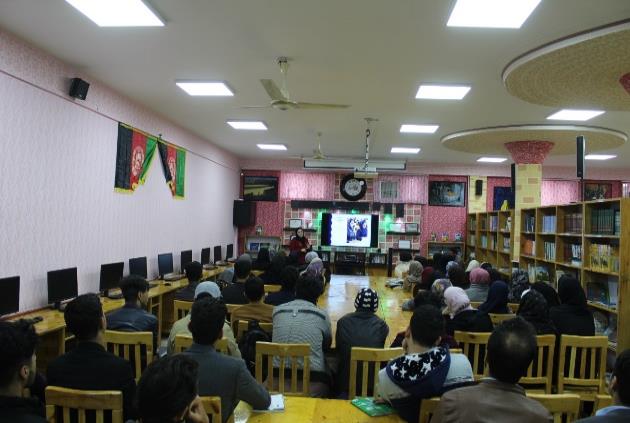large conference room with afghan flags and a presentation of unclear specificity being given.